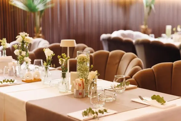 Table decor with white flowers, a candle and a lamp for a private event
